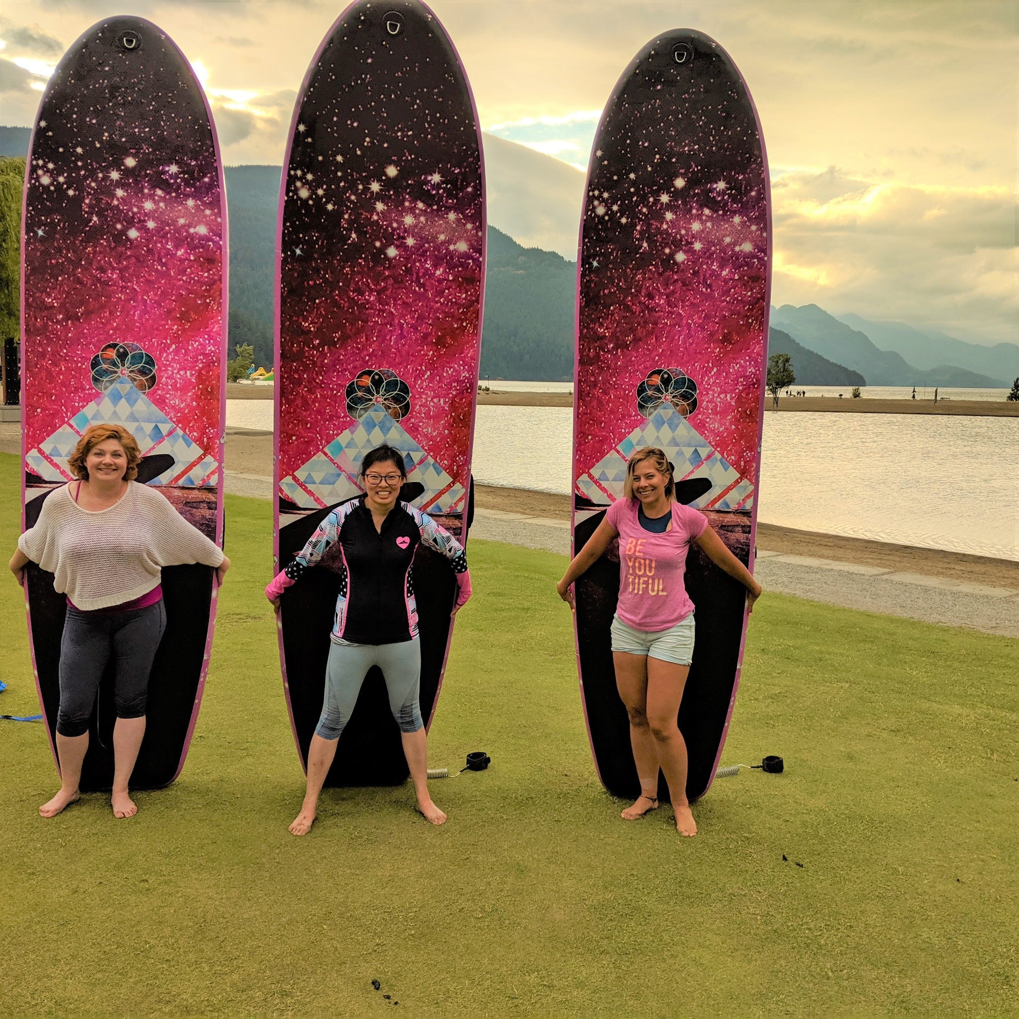 3 ladies posing with the Infinite Mantra board on the grass.